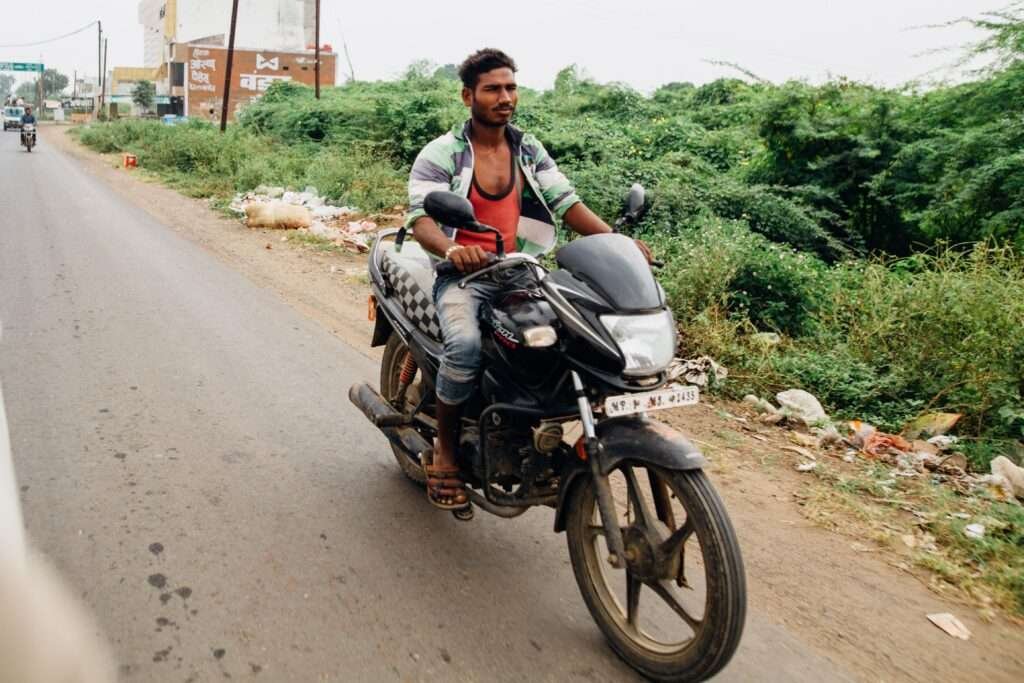 Commuter rider on a fuel-efficient motorcycle on an Indian rural road