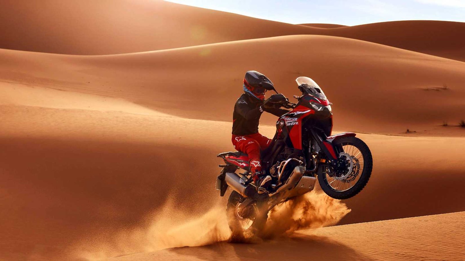 Action shot of the Africa Twin jumping over a dune